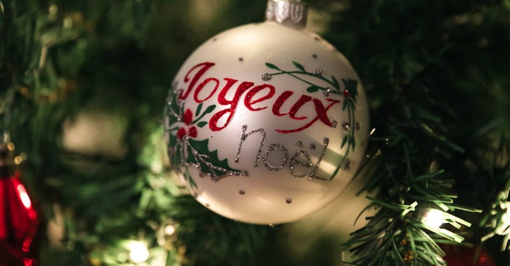 Close-up of a Joyeux Noel ornament on a decorated Christmas tree, glowing brightly.